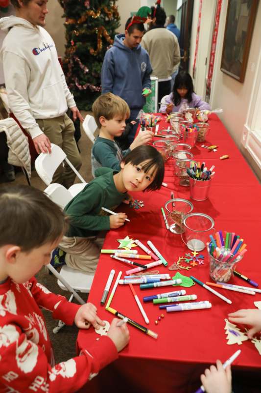 a group of kids sitting at a table with markers and paper