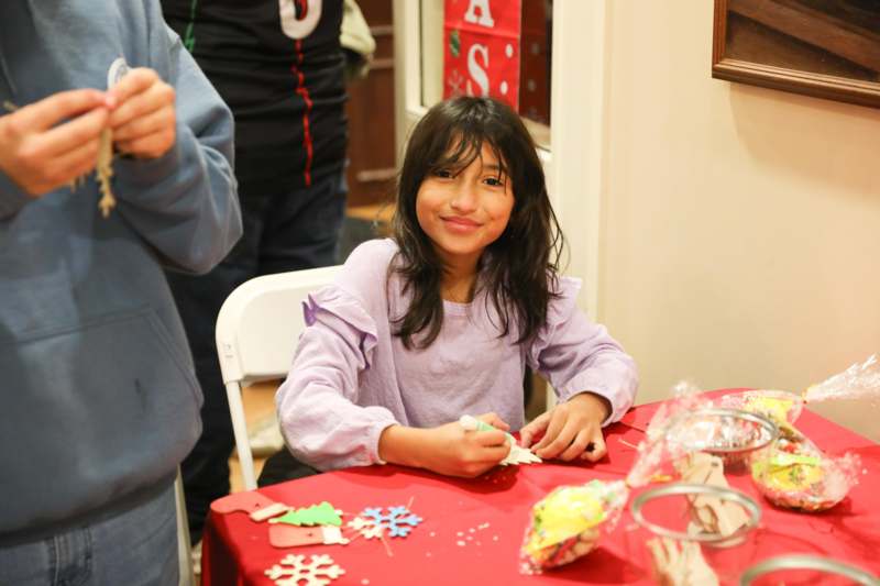 a girl sitting at a table with a red tablecloth and decorations