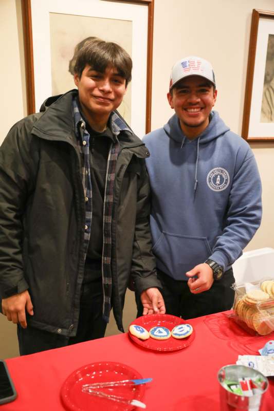 two men standing next to a table with cookies