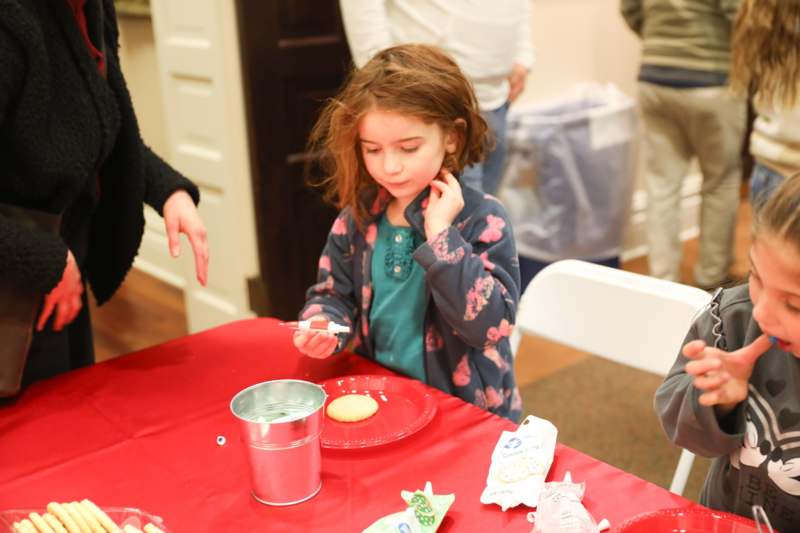a girl sitting at a table with a red tablecloth