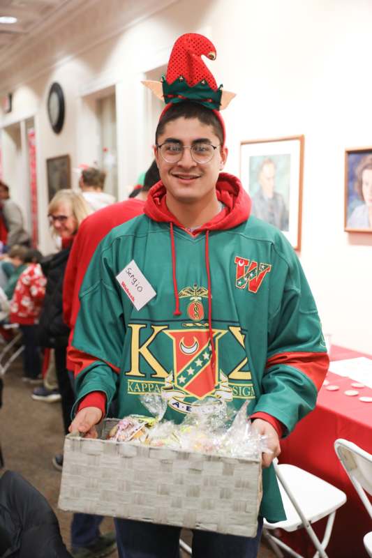 a man wearing a green and red sweatshirt holding a box of food
