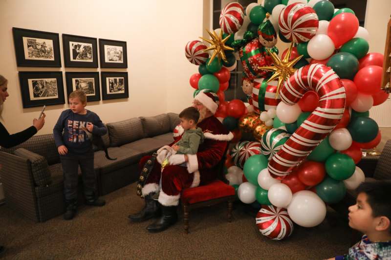 a group of kids standing next to a santa claus sitting in a chair