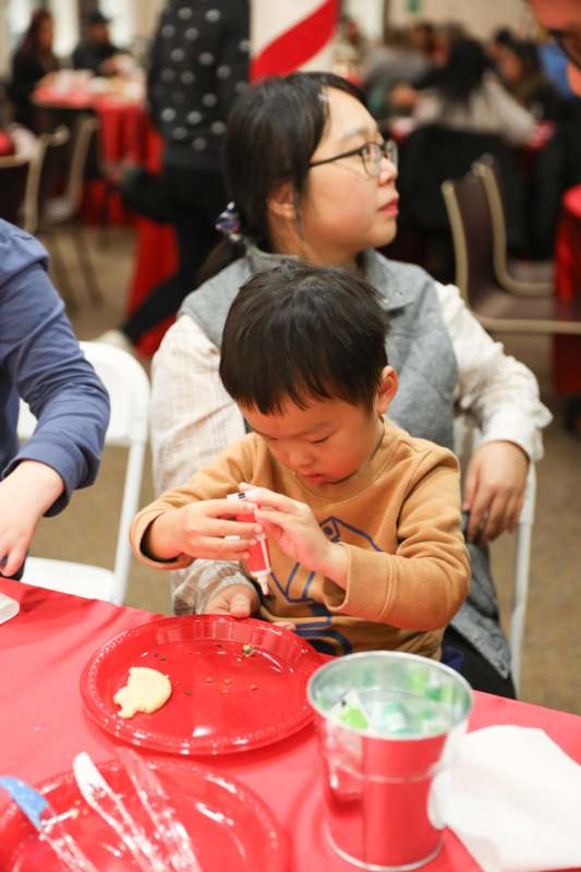 a child sitting at a table with a red tablecloth and a woman