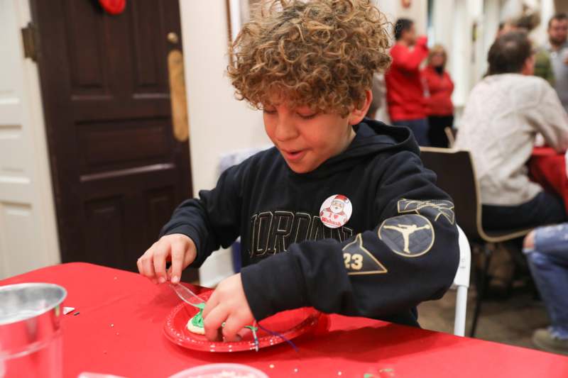a boy with curly hair making a christmas decoration