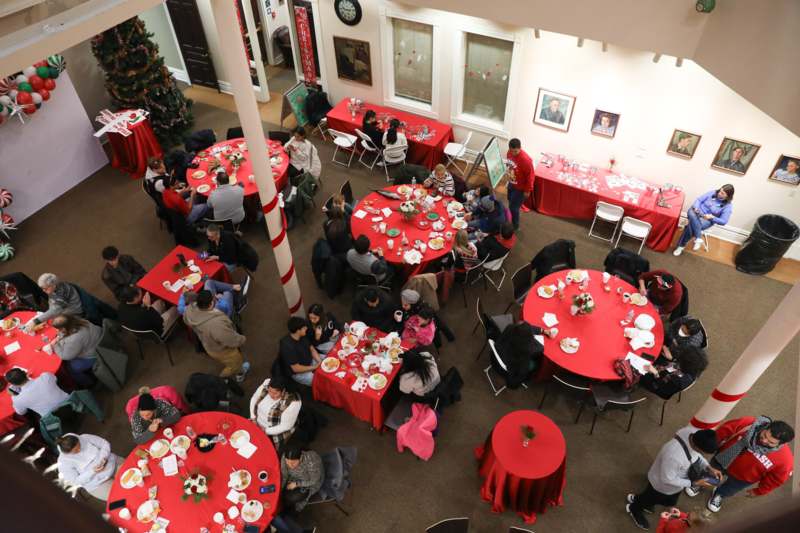 a group of people sitting at tables in a room with red tablecloths