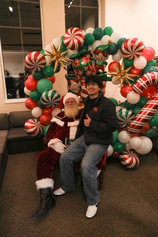 a man and santa sitting in a chair with balloons