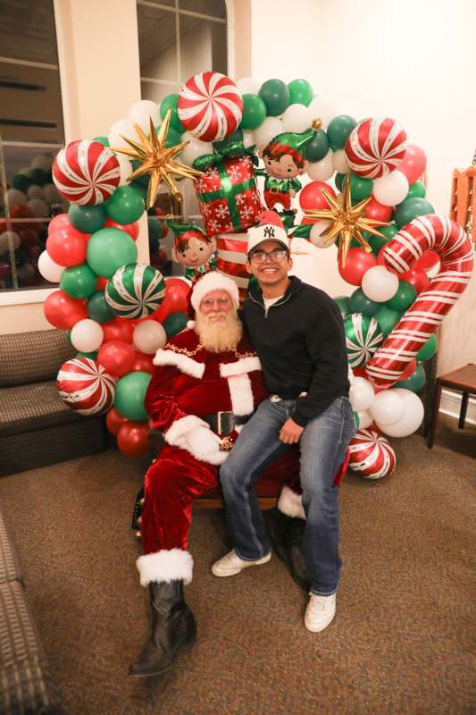 a man sitting on a chair with a santa claus in front of a christmas decoration