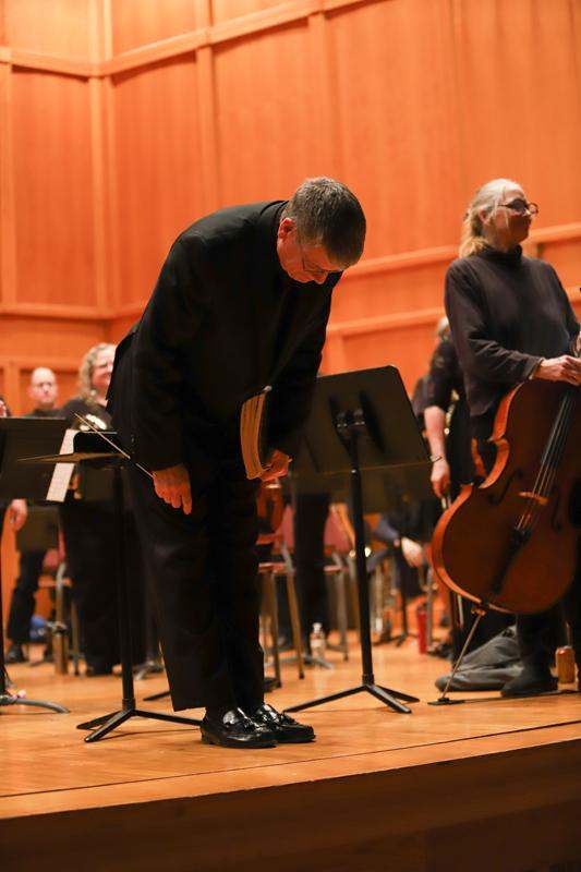 a man standing on a stage with a group of people playing instruments