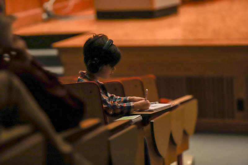 a child sitting at a desk writing on a book