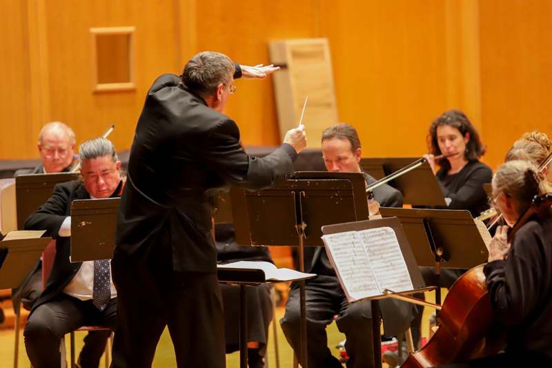 a man in a suit with a conductor in front of a group of people