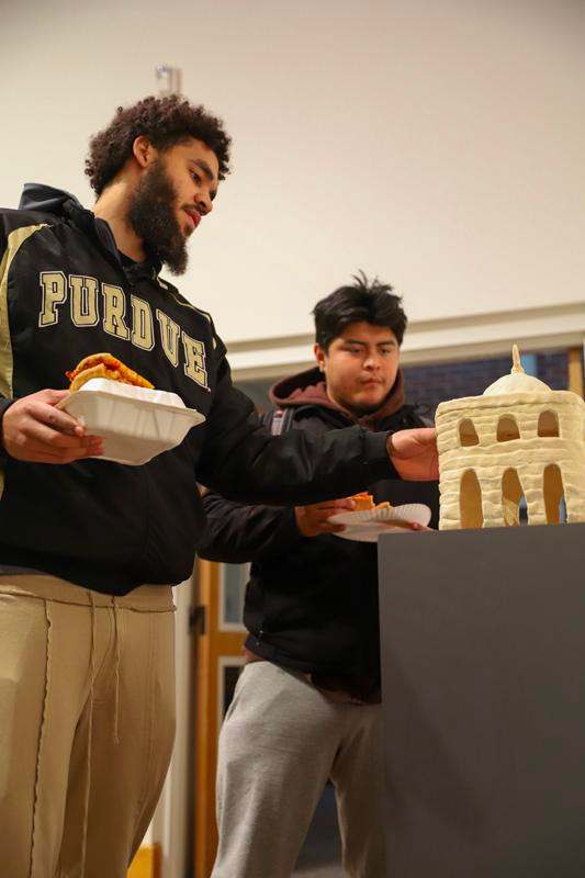 a man standing next to a man holding a tray of food