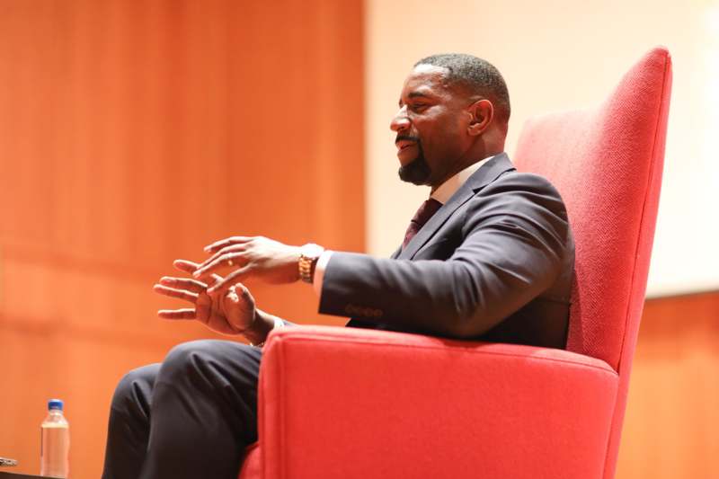 a man in a suit sitting in a red chair