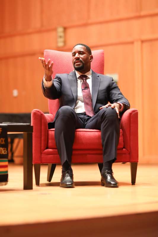 a man in a suit sitting in a red chair