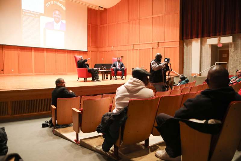 a group of people sitting in chairs in a room with a screen