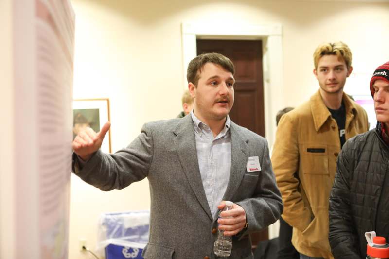 a man in a suit holding a water bottle and pointing at something