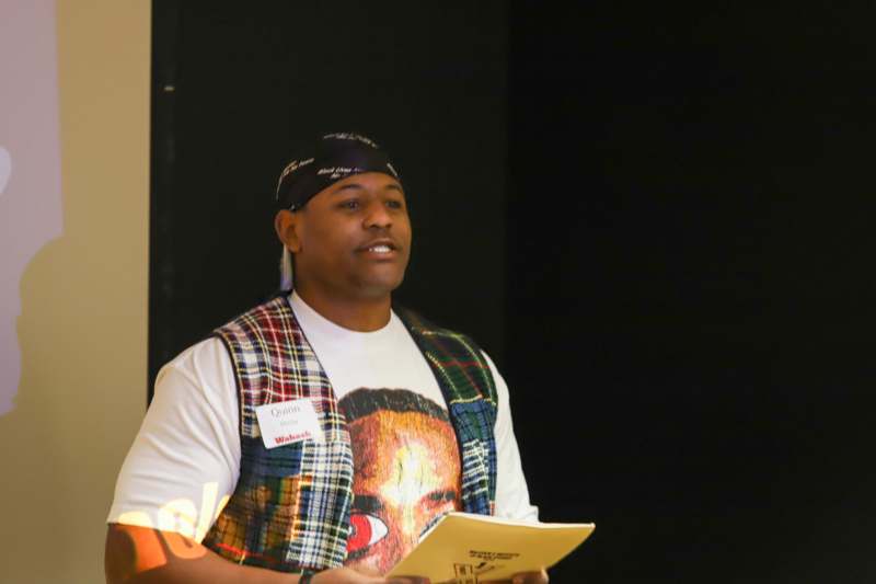 a man wearing a bandana and a scarf holding a paper