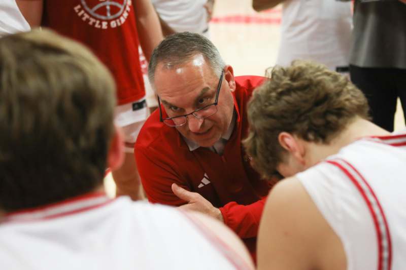 a man in a red shirt talking to a group of boys