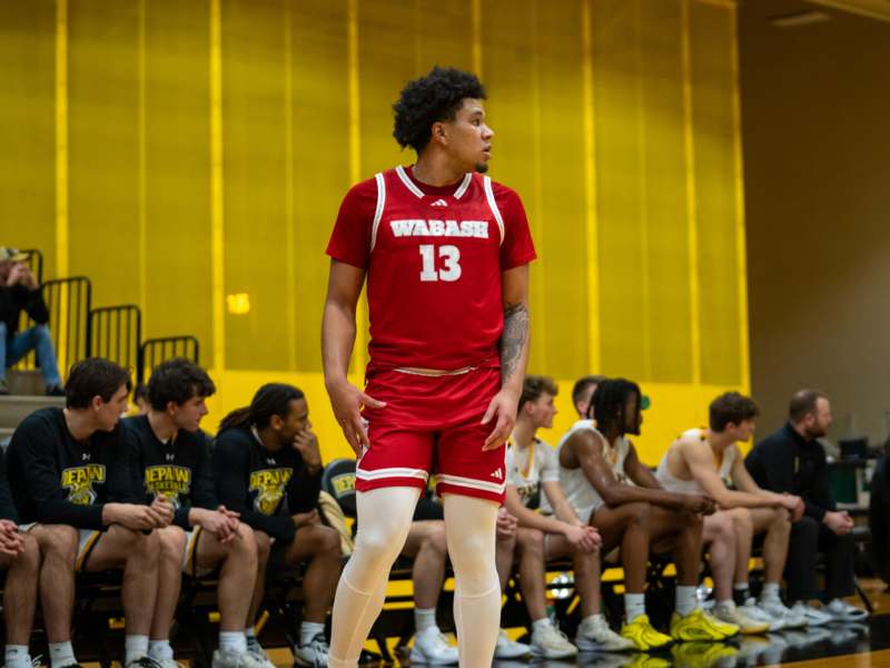 a basketball player standing in front of a group of people sitting on bench