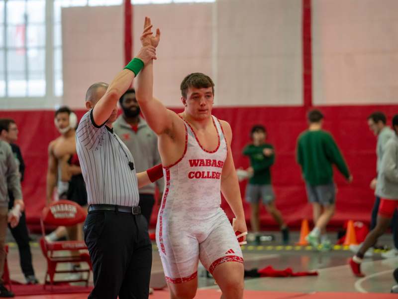 a man in a wrestling uniform raising his hand