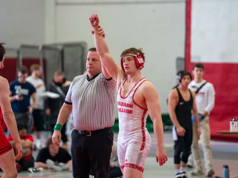 a man in a wrestling uniform raising his arm