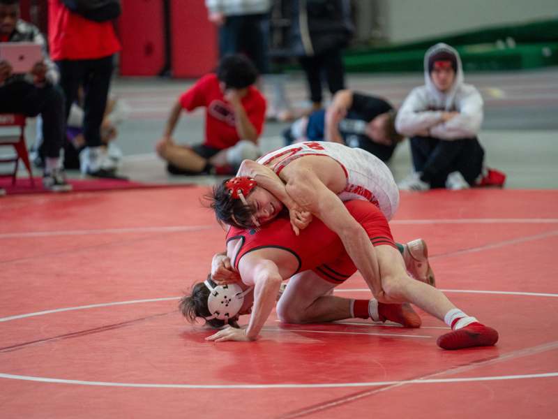 two men wrestling on a red mat