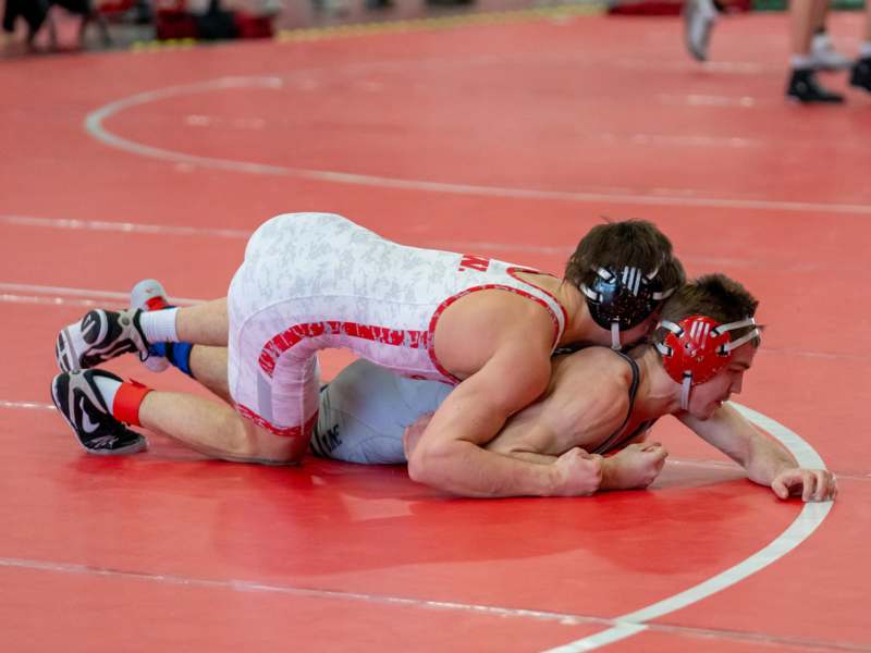 two men wrestling on a red mat