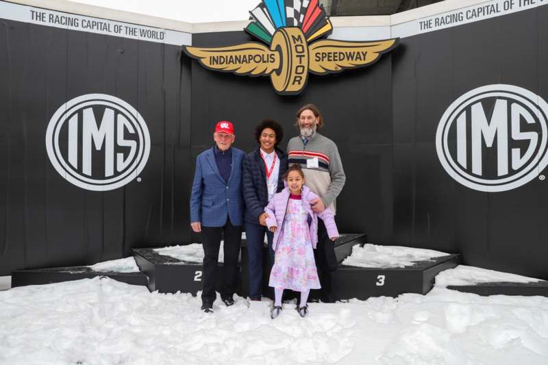 a group of people posing for a photo in front of a black sign