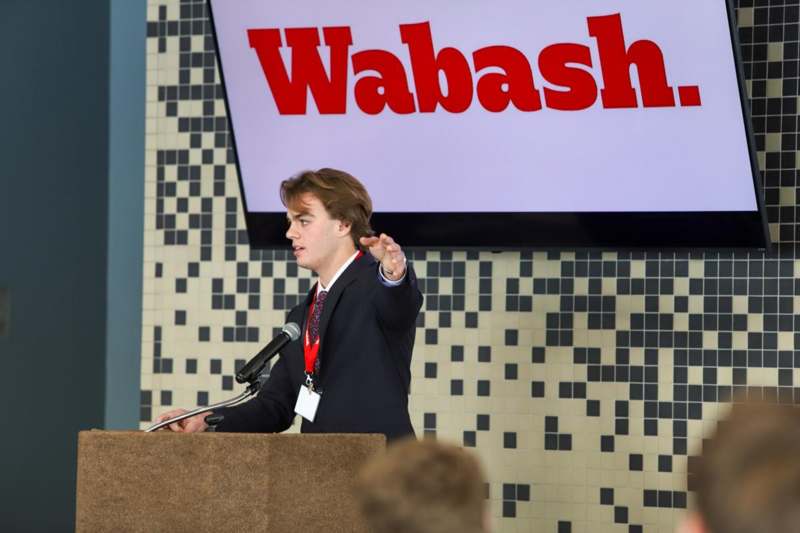 a man standing at a podium with microphones