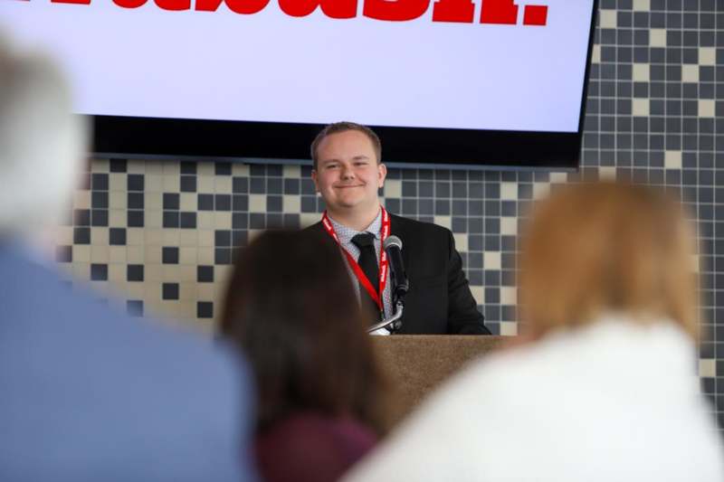 a man standing at a podium with microphones