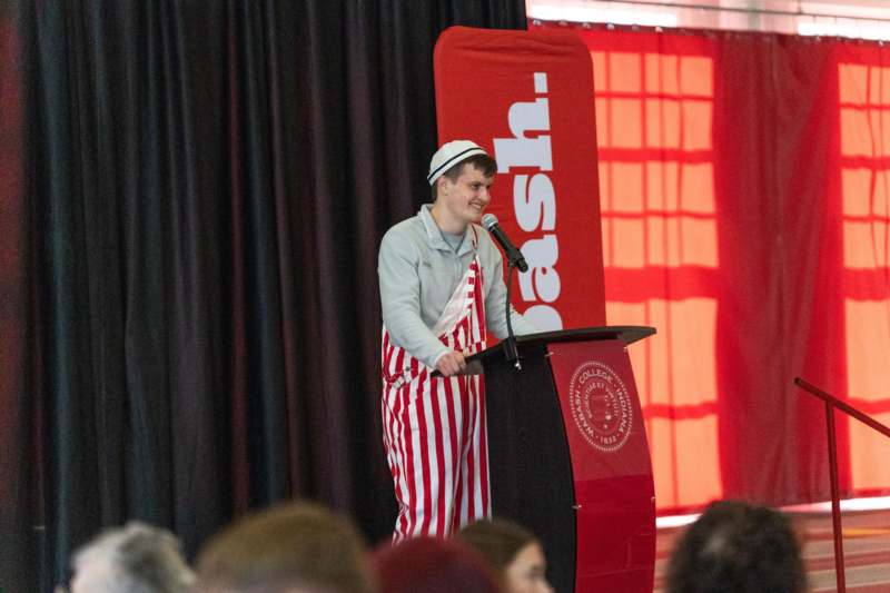 a man wearing striped apron and standing at a podium