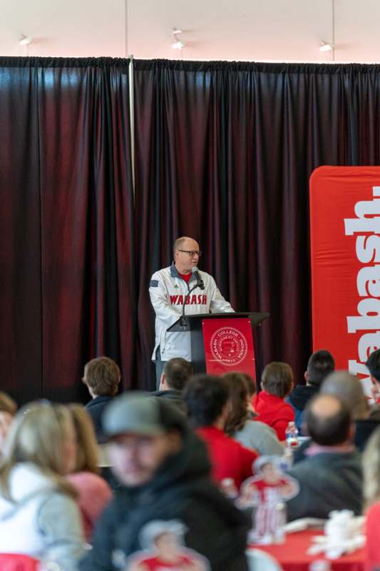 a man standing at a podium with a microphone in front of a crowd