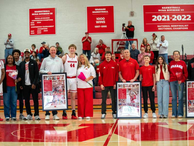 a group of people standing in a gym holding framed pictures