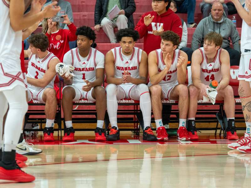 a group of men sitting on benches in a basketball game