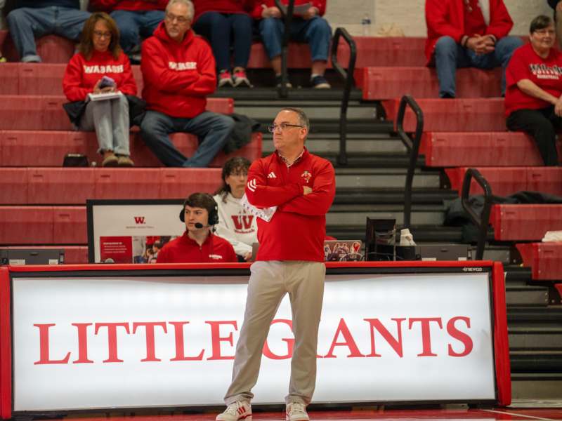 a man standing in front of a sign with his arms crossed