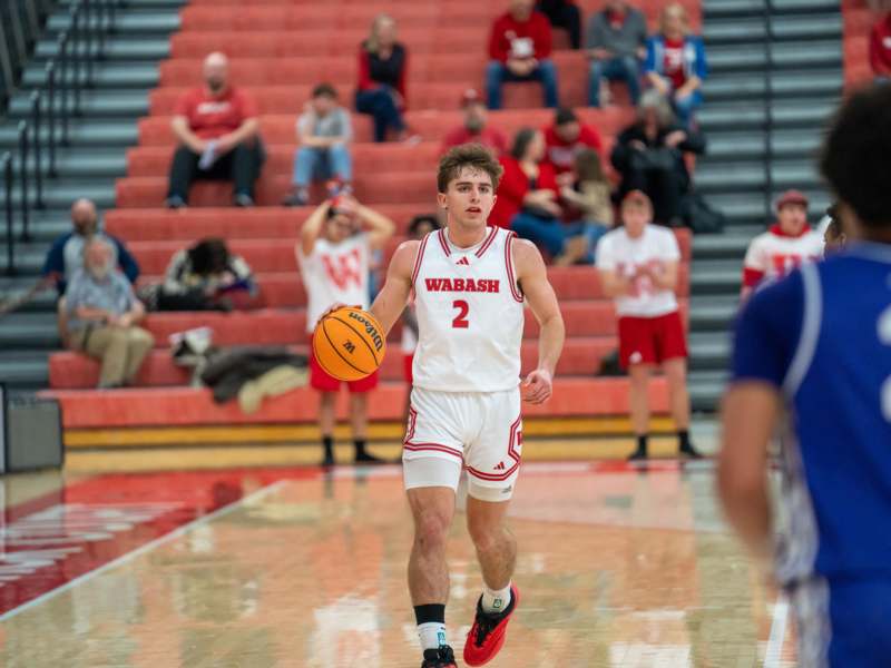 a man in a basketball uniform running with a basketball in front of a crowd