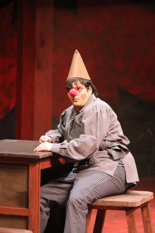 a man wearing a clown hat and sitting at a desk