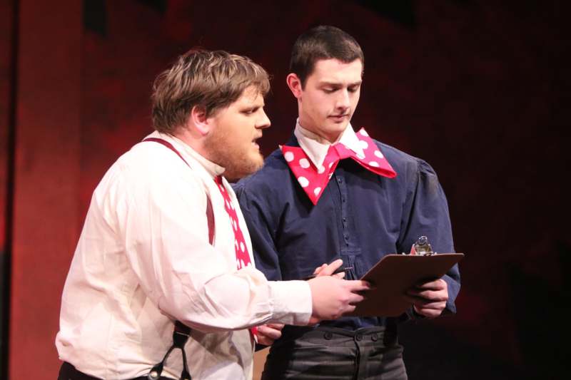 a man holding a clipboard next to a man in a red tie