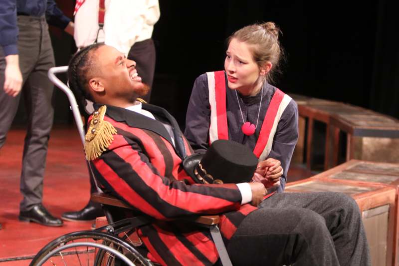 a man in a wheelchair and a woman in a red and black striped suit
