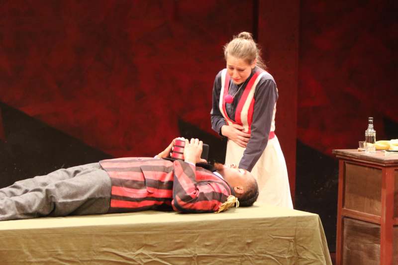 a woman standing next to a man lying on a table