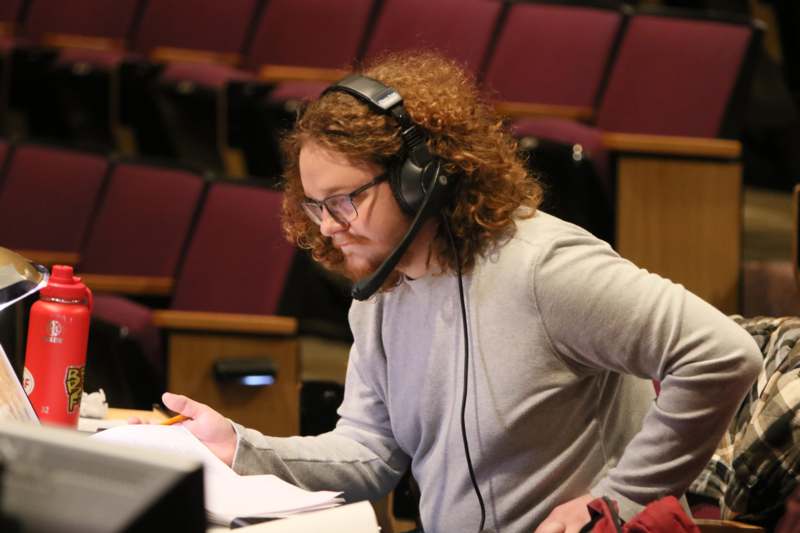 a man wearing headphones and looking at a book