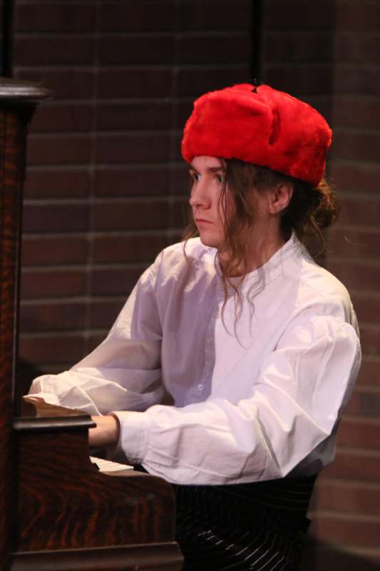 a man wearing a red hat and white shirt playing a piano