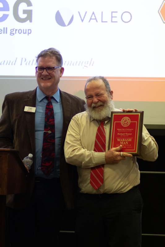 a man holding a plaque and smiling next to another man