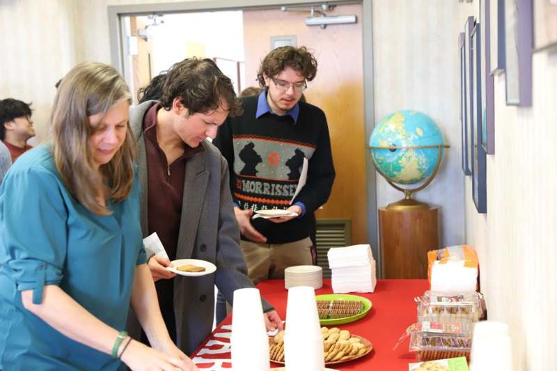 a group of people standing around a table with food