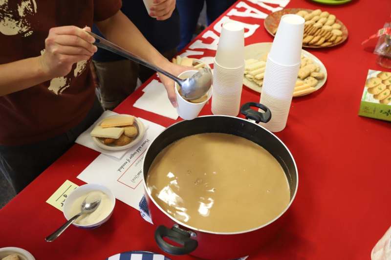 a person pouring brown liquid into a pot of food