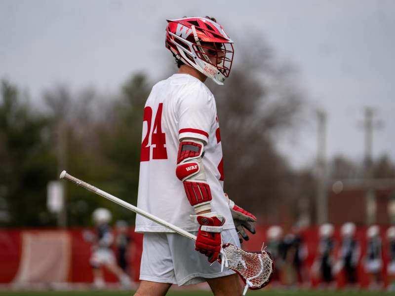 a man wearing a helmet and gloves holding a lacrosse stick