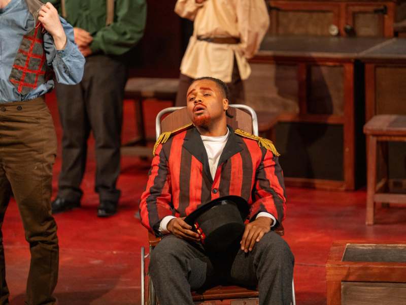 a man in a red striped suit sitting in a chair with a hat