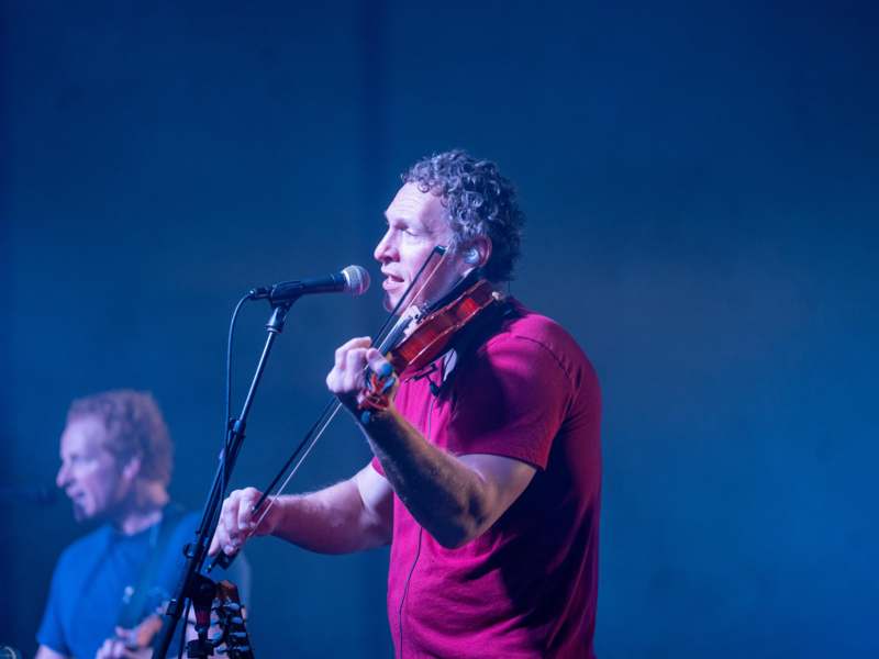 a man playing a violin and singing into a microphone