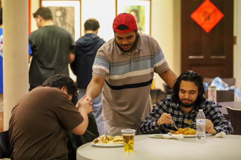 a man holding hands with another man in front of a table with food