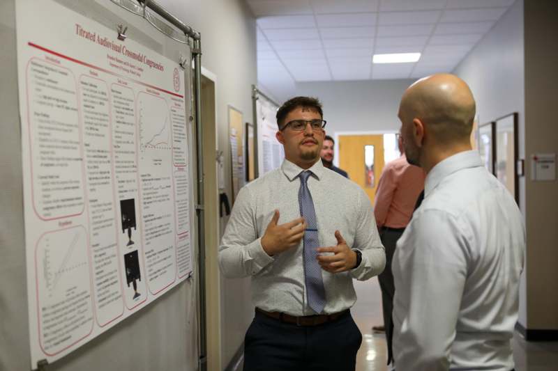 a man in a tie talking to another man in a hallway