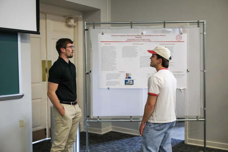 a man looking at another man standing in front of a poster